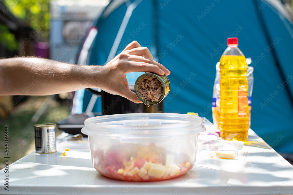 Obraz premium Crop man adding tuna in oil into salad