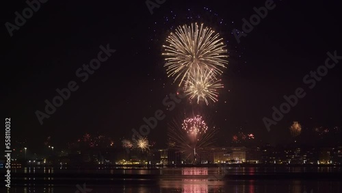 Real fireworks above large residential area landscape at night. New Years Eve pyrotechnics at Thessaloniki, Greece seen from the city waterfront.