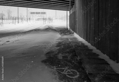 Bike path under the snow. Close-up of snow on the road. Impossible to take a bike. Snow storm. Road covered with snow in the middle of a storm  blizzard  winter. cycle route. Climate change