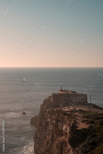 sunset on the portugese coast with a lighthouse and sailing boat 