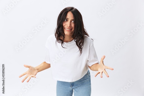 Woman in white t-shirt on white background brunette hands up gestures and signals poses in jeans emotion, lifestyle smiles, copy space
