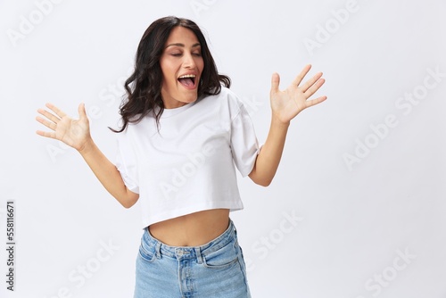 Woman in white t-shirt on white background brunette hands up gestures and signals poses in jeans emotion, lifestyle smiles, copy space