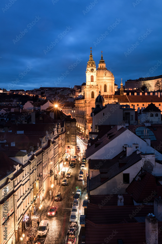 Beleuchtete Straße zur blauen Stunde mit alten Häusern und Kirche in Prag.