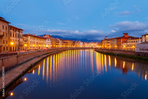 Panoramic view of the old town of Pisa and the Arno river at twilight, Italy. Night cityscape © olyasolodenko
