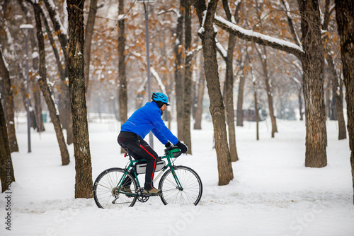 A bearded man rides a bicycle in a winter park. Eco-friendly transport in winter. Active lifestyle