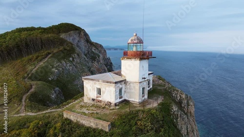 Aerial view of the old Balyuzek lighthouse on the rocky coast of the sea photo