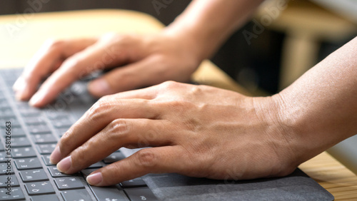 Action of a businessperson is typing on the modern design laptop keyboard to input or program data, business working concept scene. Close-up and selective focus at human hand's part.