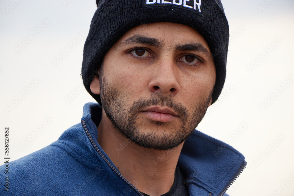 close up portrait of a young man with beard wearing ice cap in winter with face reactions. close up portrait of a young man with beard wearing ice cap in winter with face reactions.