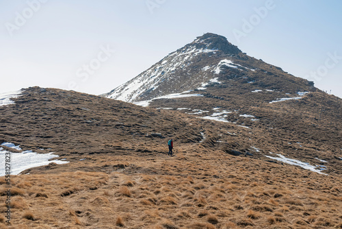 Rear view of woman with backpack looking at snow capped mountain peak Zirbitzkogel and Kreiskogel, Seetal Alps, Styria (Steiermark), Austria, Europe. Hiking trail Central Alps in sunny early spring photo