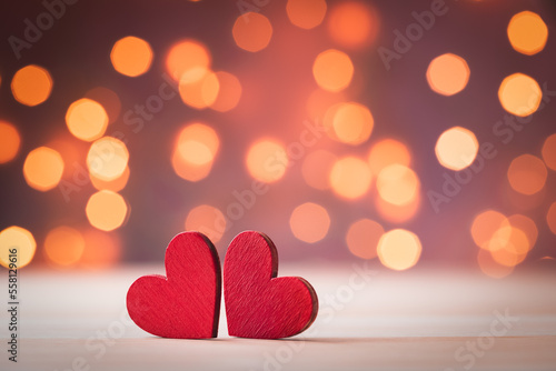 Valentine day background or greeting card with two red hearts against festive lights.