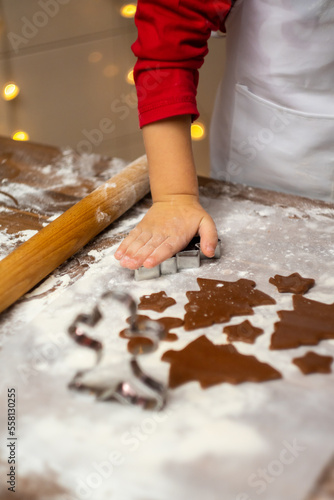 Little boy making Christmas cookies in kitchen, close up view. Vertical photo.