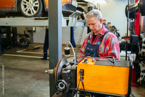 Special equipment automobile brake disk replacement in car repair shop or garage Mechanic checking car wheel rim.