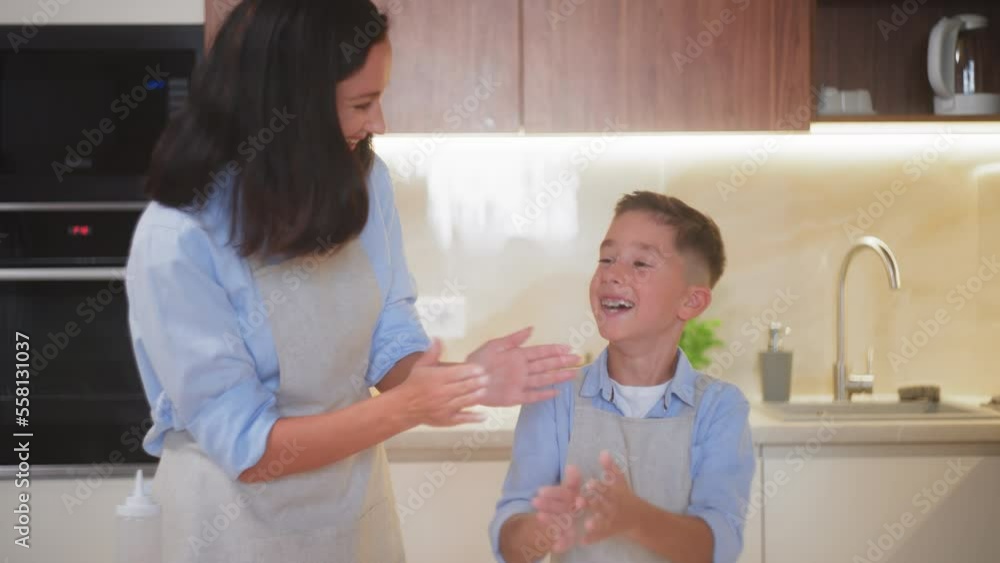 Mom and her son having fun while making dough together, homemade pizza or pie Mom and her son having fun while making dough together, homemade pizza or pie