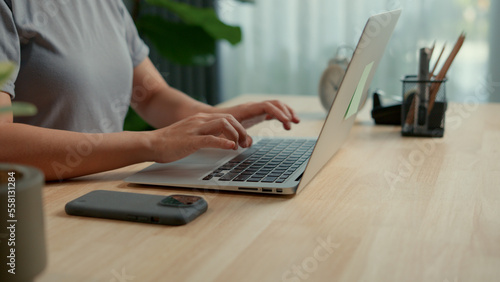 Asian woman happy typing on keyboard using laptop for work at home office.