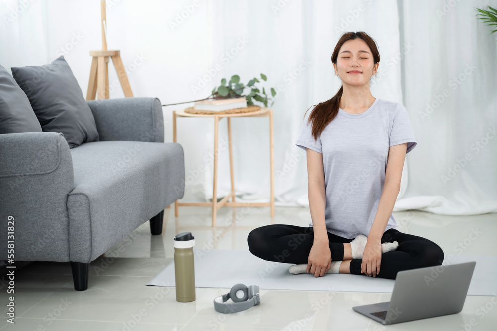 Young asian woman attractive exercises workout at home and watching Online sports tutorials over laptop