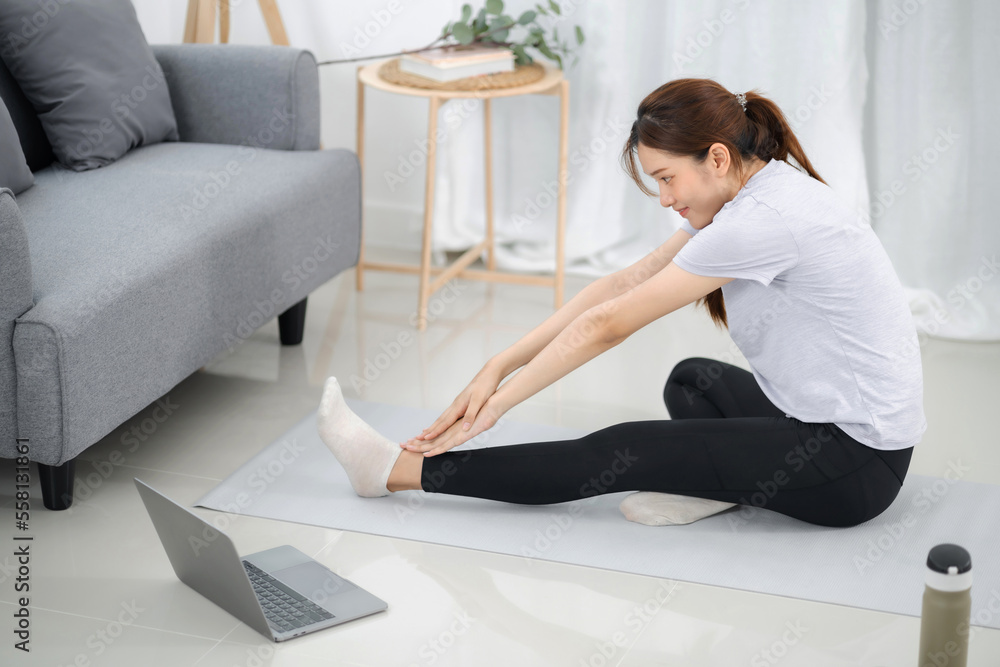 Young asian woman attractive exercises workout at home and watching Online sports tutorials over laptop Young asian woman attractive exercises workout at home and watching Online sports tutorials over laptop