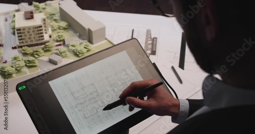 Man architect uses tablet computer and draws project of building