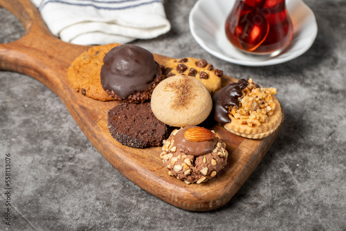 Sweet cookies on a dark background. Varieties of chocolate, hazelnut and pistachio cookies on a wooden serving plate. close up