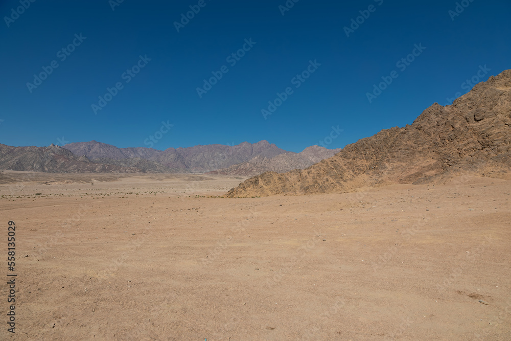 Beautiful stone mountains in the desert. Yellow sand on the mountains. Evening nature. Sunny summer day.
