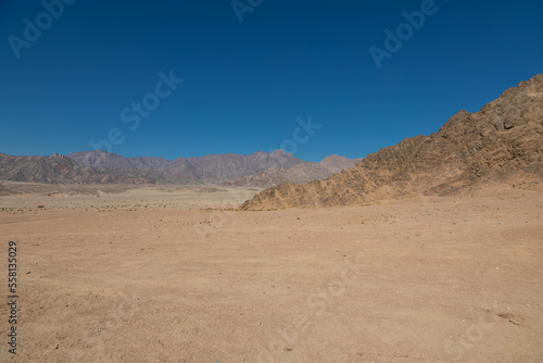 Beautiful stone mountains in the desert. Yellow sand on the mountains. Evening nature. Sunny summer day. © Kooper