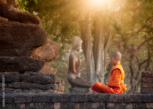 Buddhist monk and novice meditation in front of the Buddha statue at the old temple