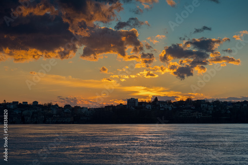 sky with cloud over ice covered lake during thaw, reflection of sunset on ice
