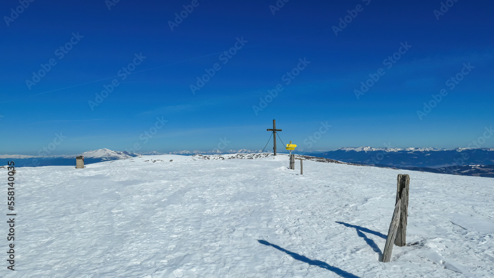 Hiking trail along a fence leading to the summit cross of mountain peak Ladinger Spitz, Saualpe, Lavanttal Alps, border Styria Carinthia, Austria, Europe. Hiking trail in Wolfsberg on sunny winter day Hiking trail along a fence leading to the summit cross of mountain peak Ladinger Spitz, Saualpe, Lavanttal Alps, border Styria Carinthia, Austria, Europe. Hiking trail in Wolfsberg on sunny winter day