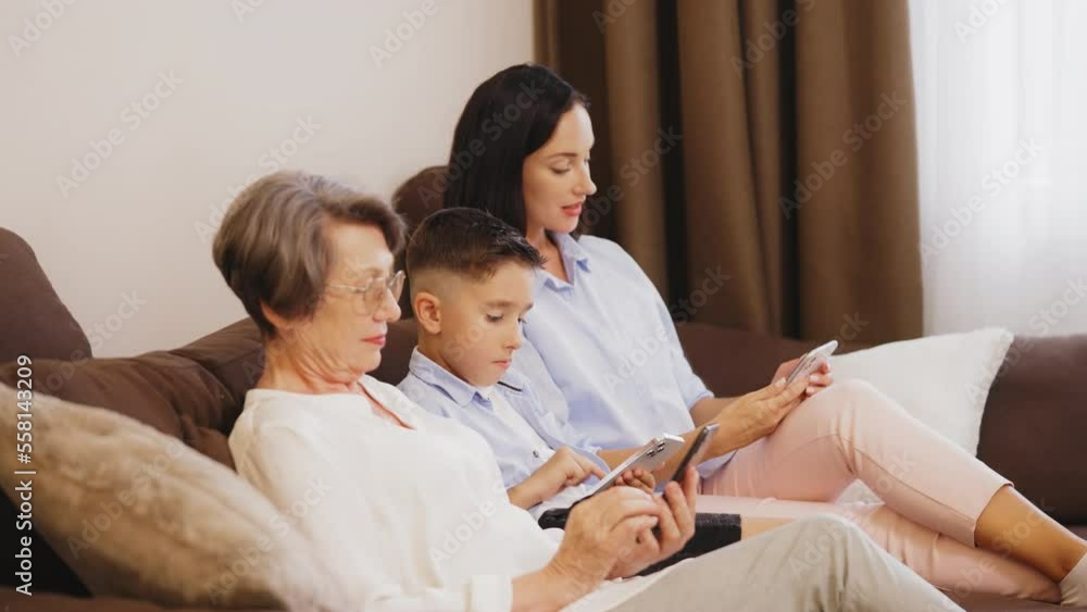 Senior mother, her adult daughter and grandson using their smartphones at home Senior mother, her adult daughter and grandson using their smartphones at home