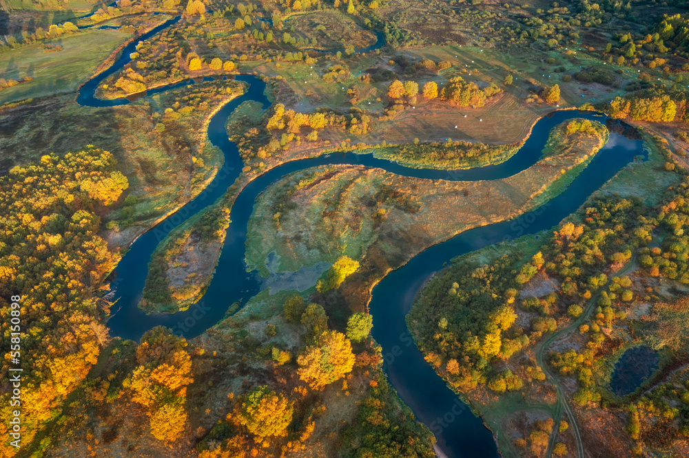 Aerial view of landscape of beautiful nature. Autumn morning above meadow and meadering river. Country roads on meadow.