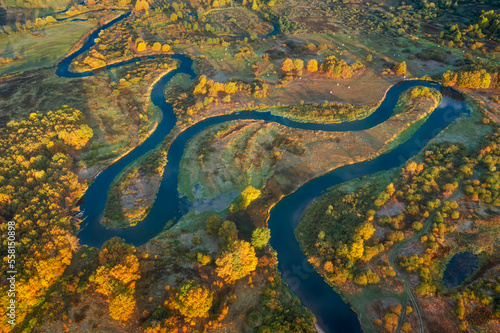 Aerial view of landscape of beautiful nature. Autumn morning above meadow and meadering river. Country roads on meadow.  