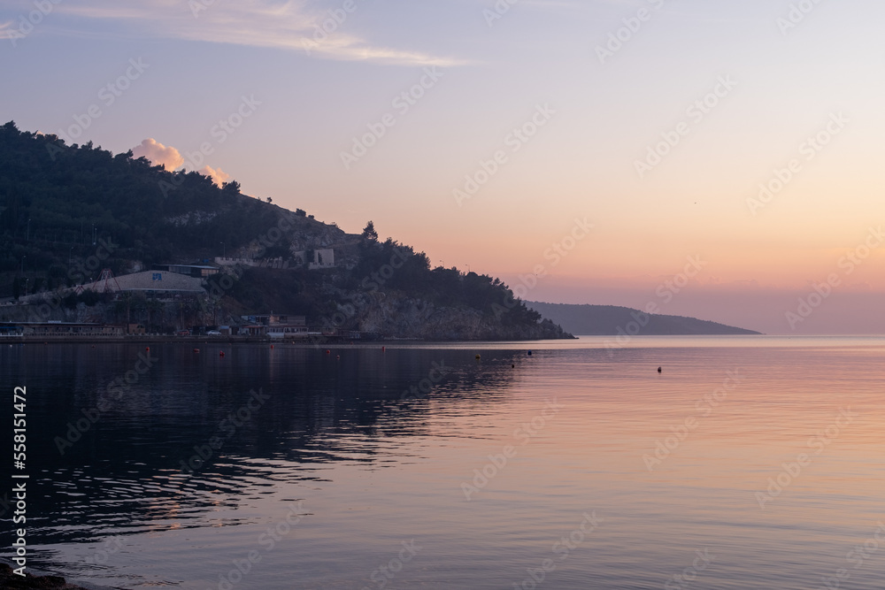 the land reflected on the still water and the island landscape behind the haze in the background. A peaceful sunset the land reflected on the still water and the island landscape behind the haze in the background. A peaceful sunset