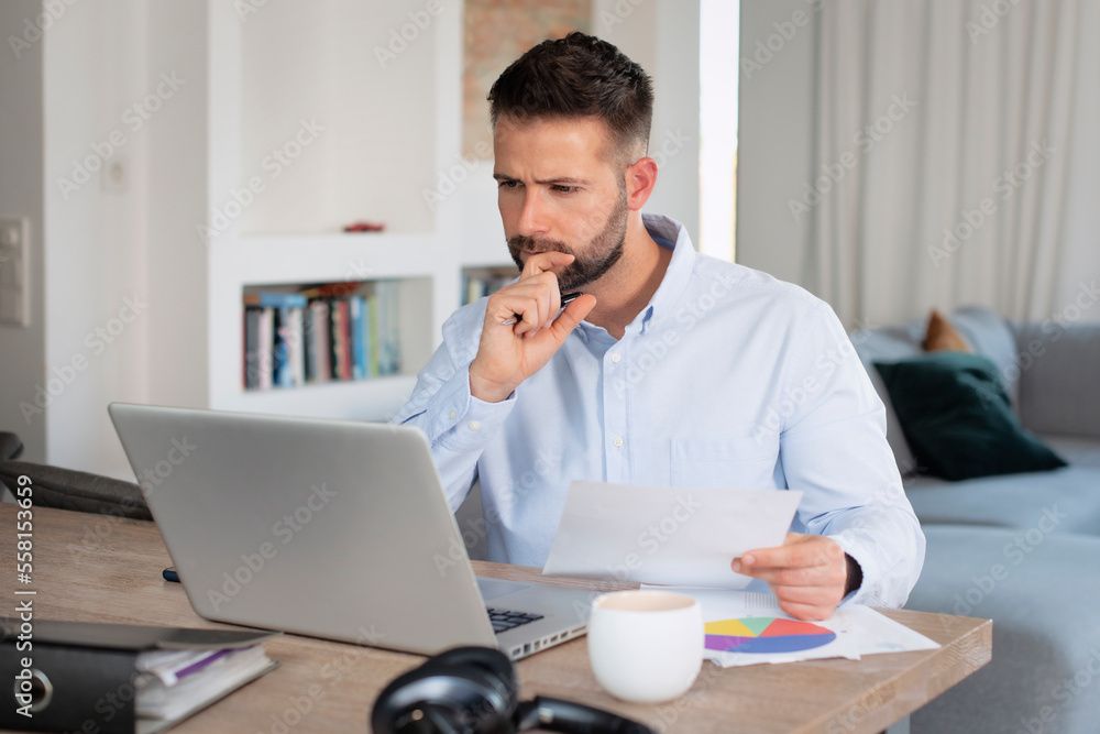Confident businessman using laptop while working from home Confident businessman using laptop while working from home