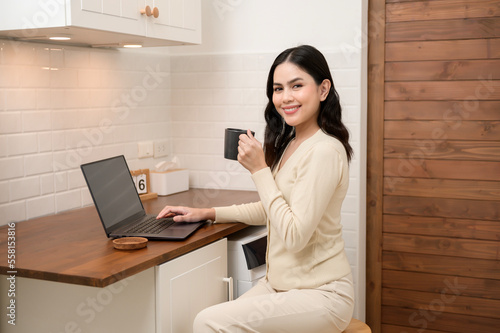 An Asian young woman using laptop computer online working at home , lifestyle and teleworking concept