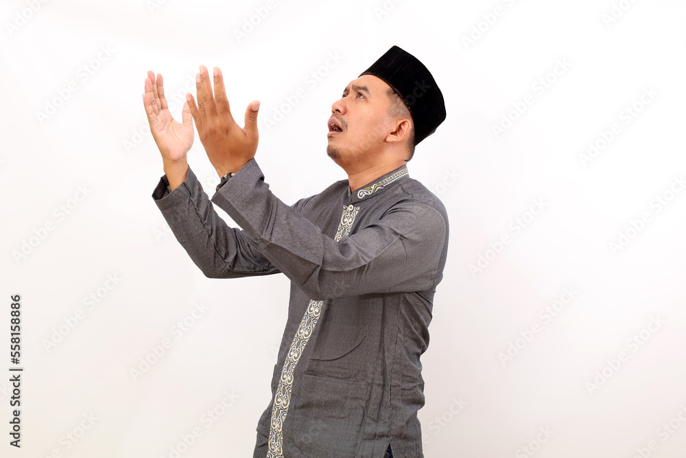 Asian muslim man standing with praying and hoping gesture. Isolated on white background