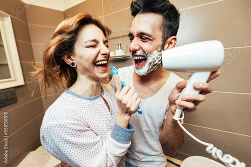 Canvas Print Husband and wife sharing bathroom together at home shaving beard and washing tee
