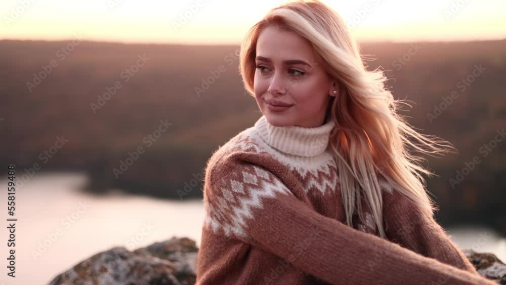 Cinematic shot of calm young lady sitting on the rock in the mountains with beautiful pink sunset. Inspiration. Harmony. Woman with nature. Cinematic shot of calm young lady sitting on the rock in the mountains with beautiful pink sunset. Inspiration. Harmony. Woman with nature.