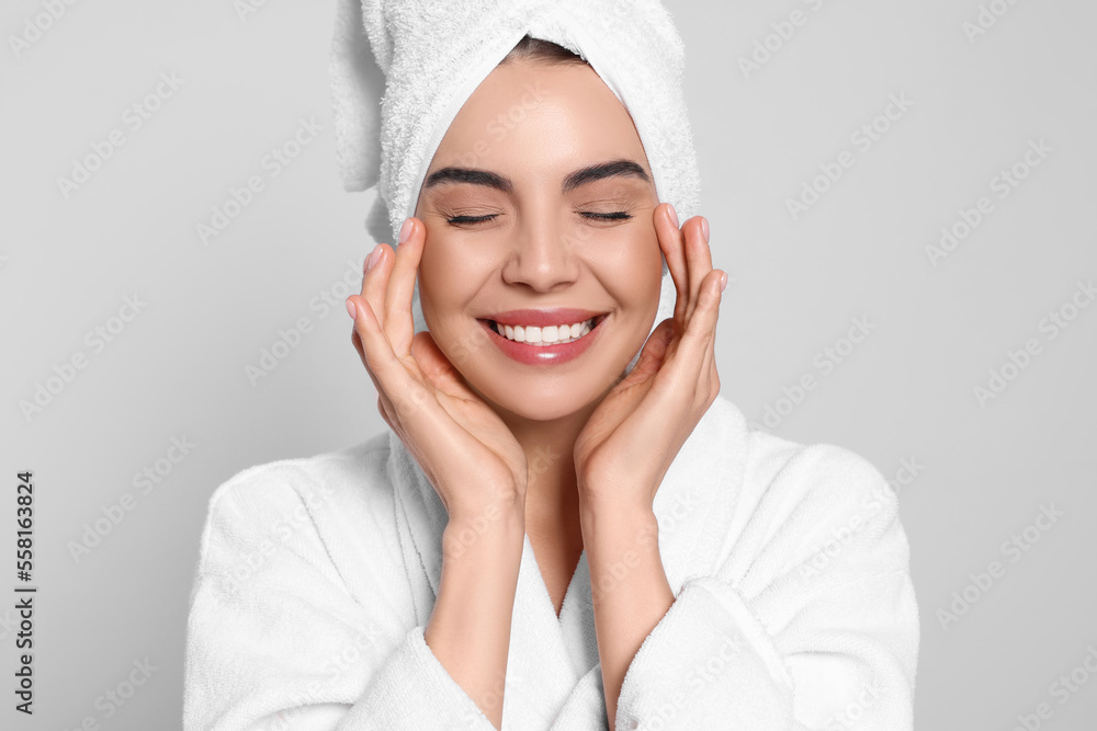 Young woman in bathrobe with towel on light grey background. Spa treatment Young woman in bathrobe with towel on light grey background. Spa treatment