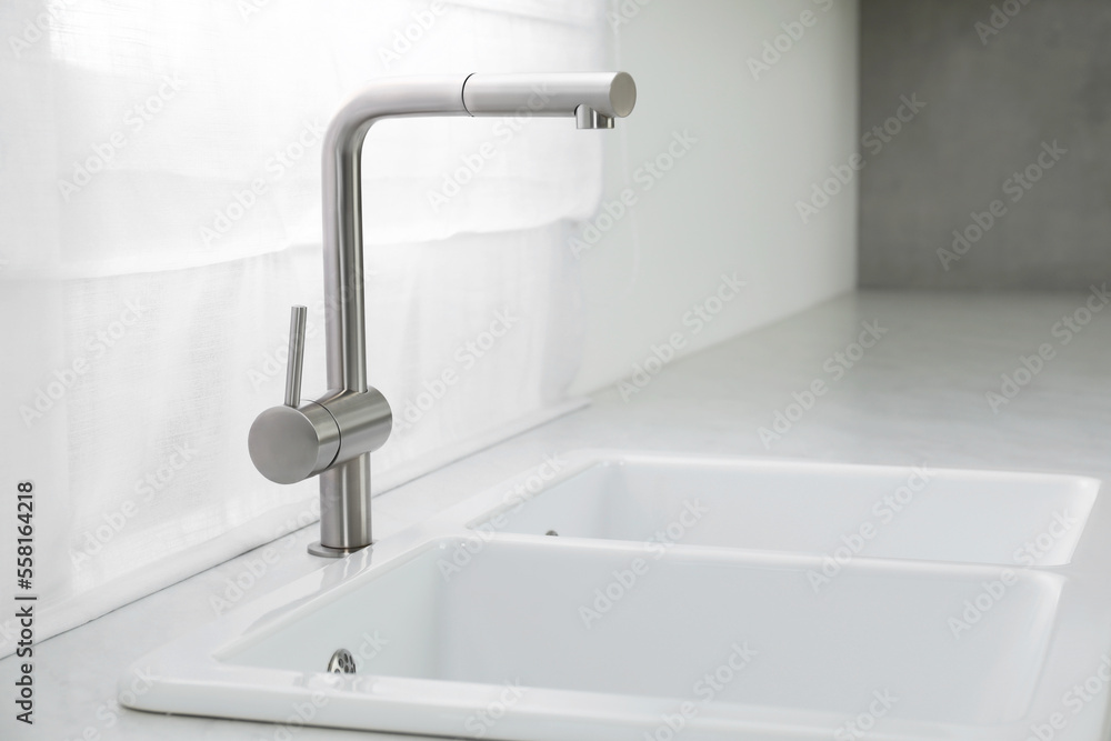 Modern sink and water tap near window in kitchen. Interior design Modern sink and water tap near window in kitchen. Interior design