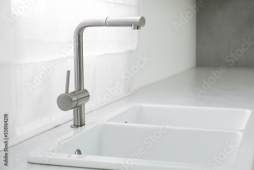 Modern sink and water tap near window in kitchen. Interior design