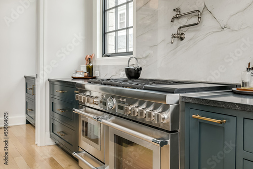 Transitional Kitchen with Stainless Steel Luxury Appliances. Transitional kitchen design with marble backsplash. Styled counter and stove with pot filler.