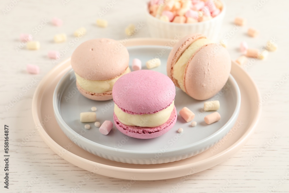 Delicious colorful macarons and marshmallows on white wooden table