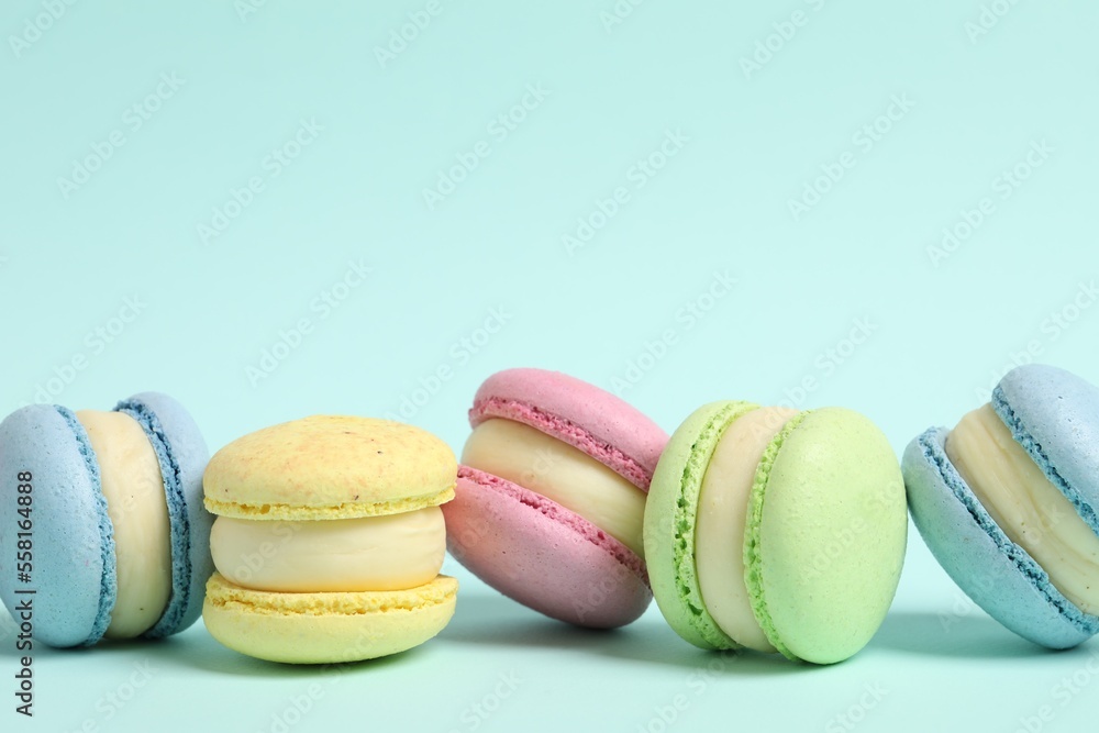 Delicious colorful macarons on light blue background, space for text Delicious colorful macarons on light blue background, space for text