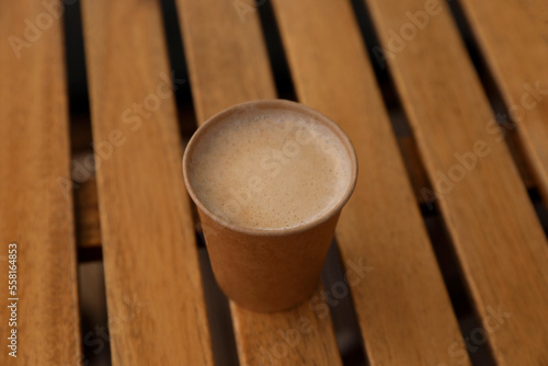 Takeaway paper cup with coffee on wooden table