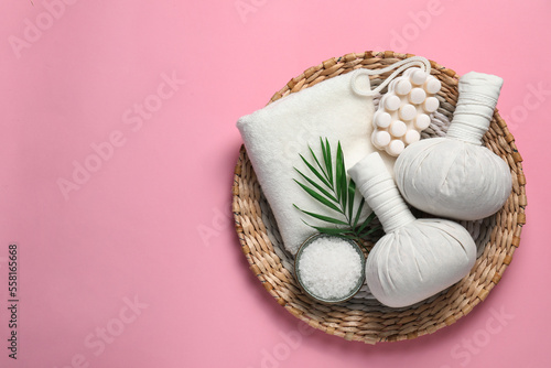 Beautiful spa composition with herbal massage bags and different care products on pink background, flat lay. Space for text