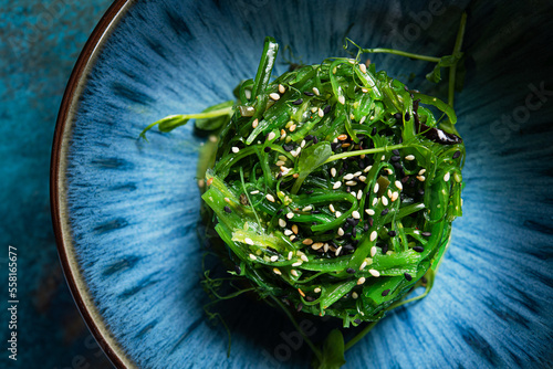 Fresh seaweed salad with sesame on a blue abstract plate