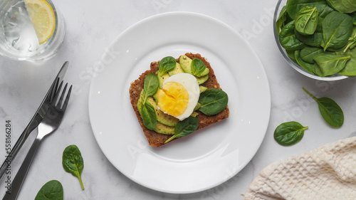 Tasty sandwich with boiled egg, avocado and spinach served on white marble table, flat lay