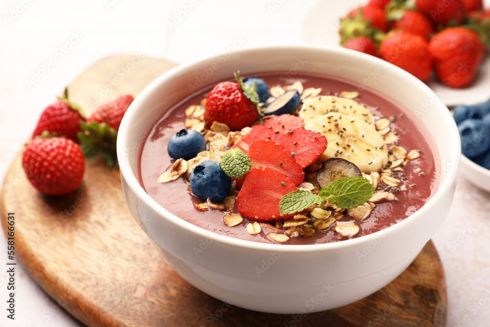 Delicious smoothie bowl with fresh berries, banana and granola on table, closeup Delicious smoothie bowl with fresh berries, banana and granola on table, closeup