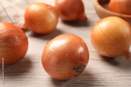 Many ripe onions on wooden table  closeup