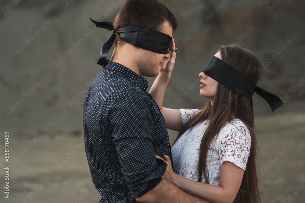 Romantic couple blindfolded with black ribbon touching each other. Love blind concept