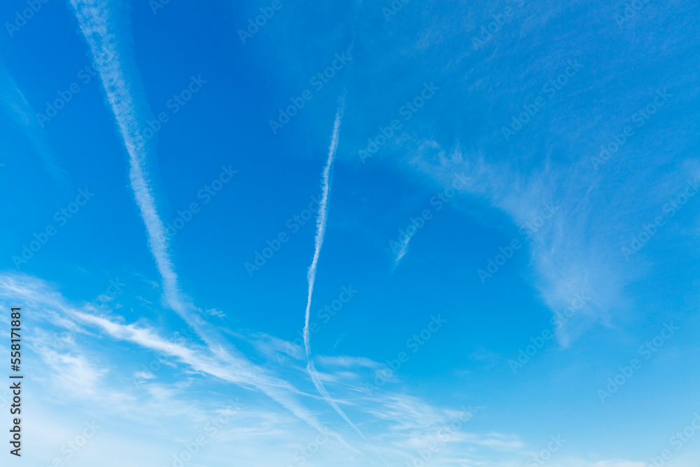 A bright blue sky with traces of condensation from airplanes. Space for text. A bright blue sky with traces of condensation from airplanes. Space for text.